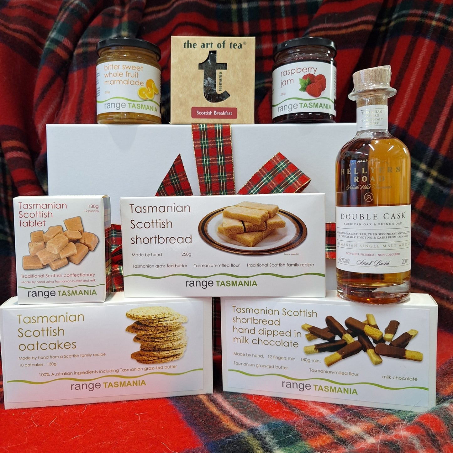 Collection of Tasmania range products including a bottle, jars, and boxes on a plaid fabric background.