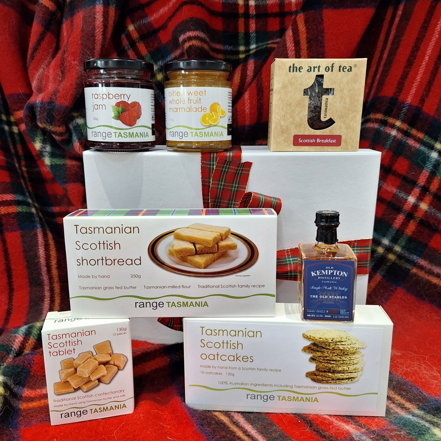 Assorted food products including tea, jam, and shortbread on a plaid fabric background